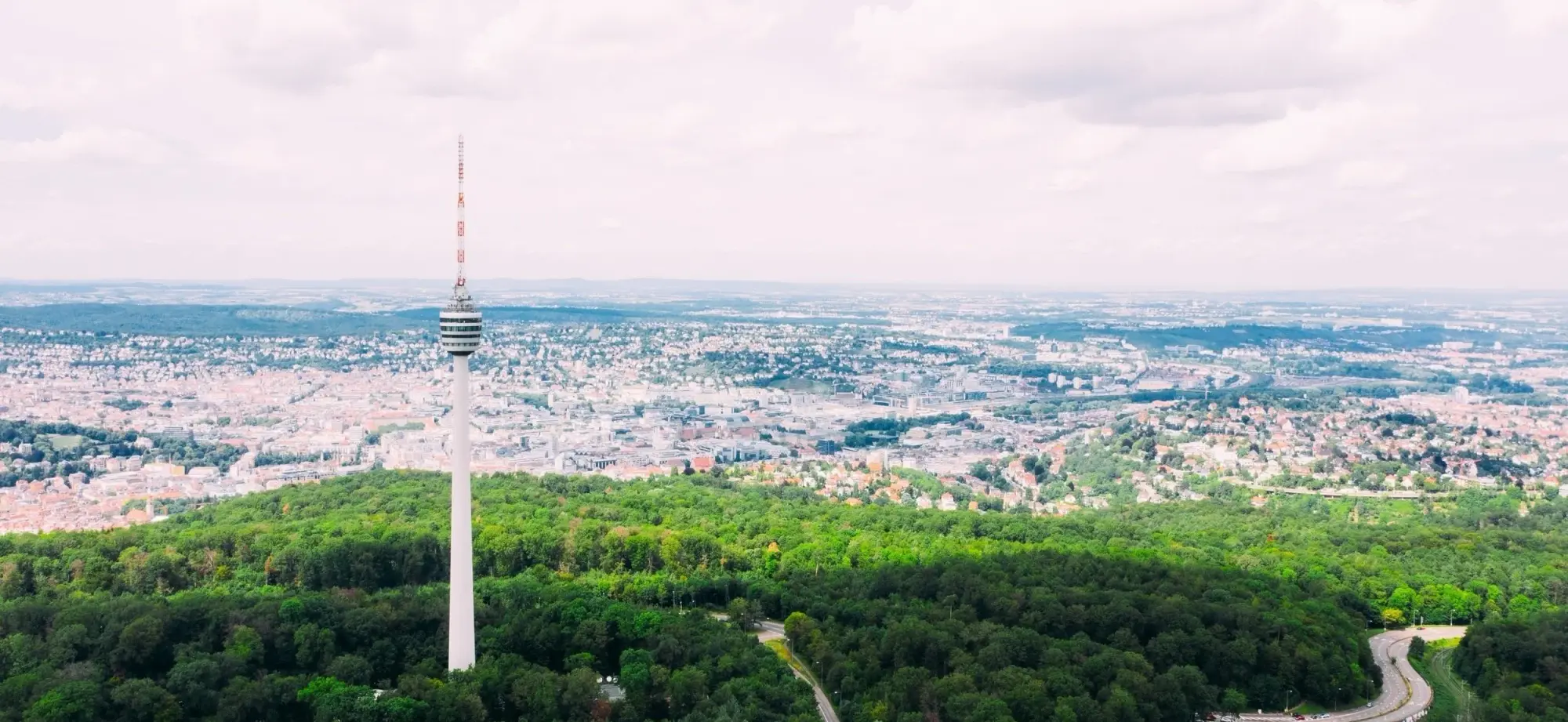 Fernsehturm mit Aussichtsplattform über bewaldetem Hügel