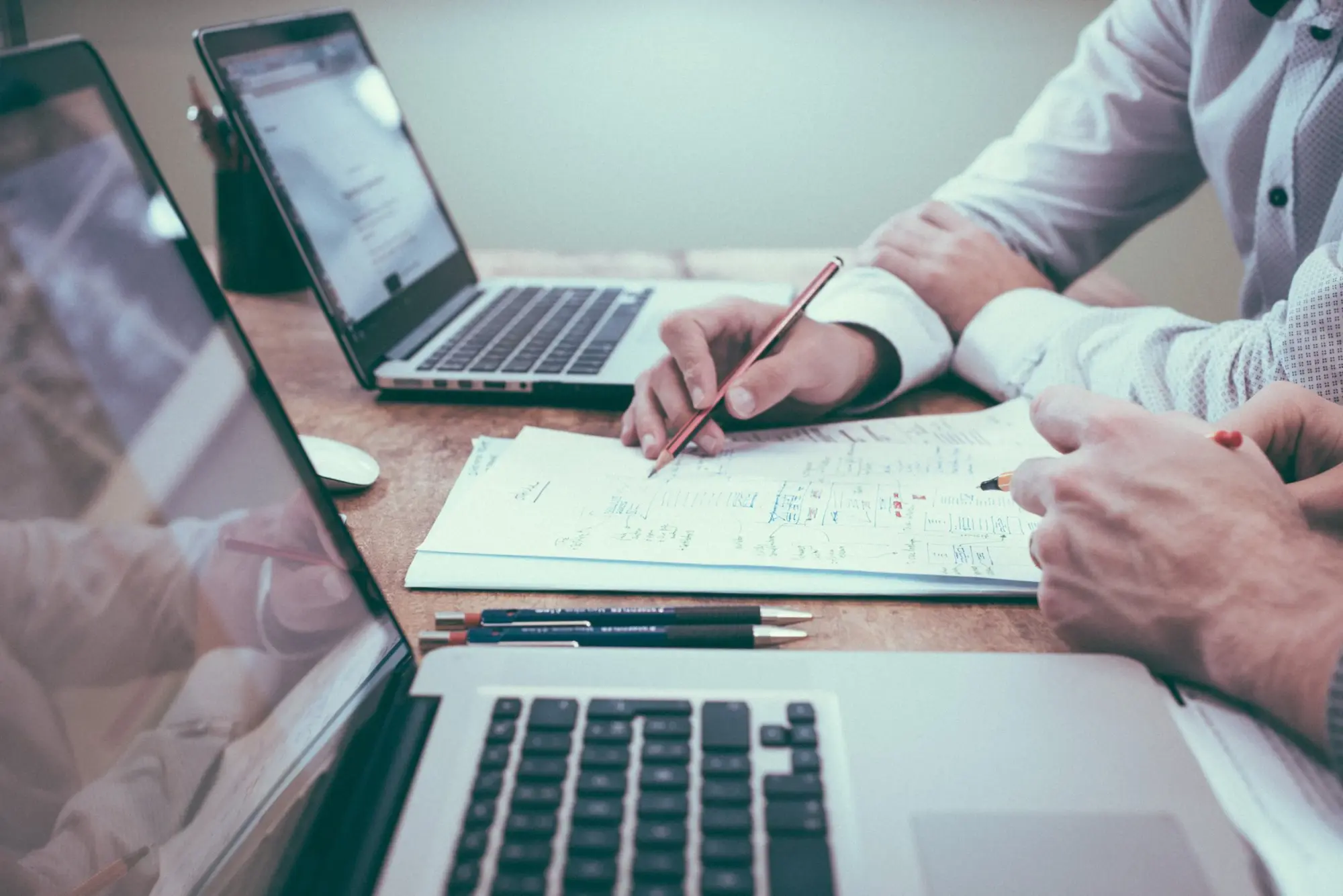 Person arbeitet am Laptop vor Notizpapier